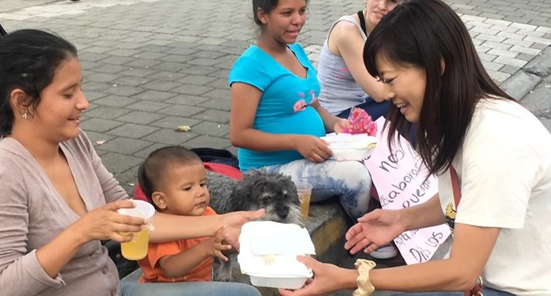 Yoriko gives a meal to a Venezuelan family in Medellin Colombia